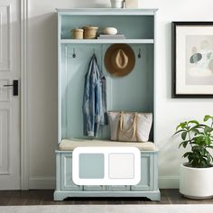 a blue coat rack with two coats hanging on it's sides and a white purse in front of it