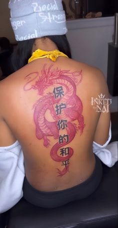 the back of a woman's body with chinese writing on it and a dragon tattoo