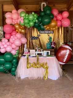 a baby shower table with balloons and footballs