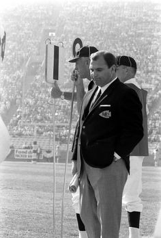 a man in a suit and tie standing next to another man on a football field