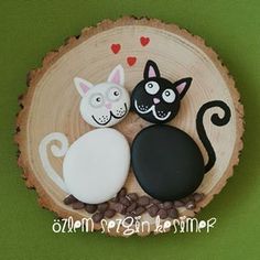 three decorated cookies sitting on top of a wooden slice in the shape of two cats