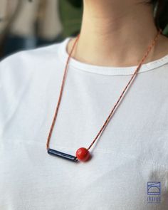 MATERIALS: This mid-century modern design ceramic necklace's minimal geometric pendants are made using white earthenware clay carefully sculpted and shaped by hand, glazed with vibrant red and dark blue metallic effect high-quality glossy glazes.  This statement pottery necklace features an adjustable, 2mm thick, multicolor (orange, blue-red striped) durable nylon paracord rope, ensuring comfort and durability. DIMENSIONS: The ball-shaped vibrant red pendant measures 0.6 inches in diameter, and the bar-shaped pendant measures approximately 1.8x0.25 inches (4.6x0.65 cm). The multicolor necklace cord is customizable from 17 to 31.5 inches (43 to 80 cm). The adjustable mechanism allows you to easily slide and secure the cord at your desired length, allowing you to create different looks and a Modern Red Necklace For Gift, Red Metal Necklace With Large Pendant, Modern Red Adjustable Necklace, Red Handmade Enamel Necklaces, Handmade Red Enamel Necklace, Paracord Rope, Pottery Necklace, Ceramic Pendants, Red Pendant