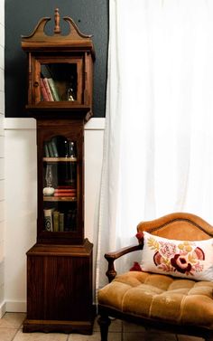 an old grandfather clock sitting next to a chair