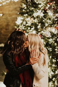 two women kissing in front of a christmas tree