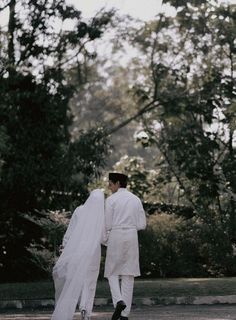 a bride and groom walking through the park