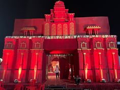 a large red building with lots of lights on it's sides and people standing in the doorway