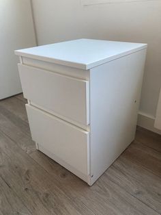 a white filing cabinet sitting on top of a hard wood floor