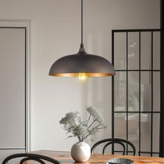 a wooden table with black chairs and a white vase on it