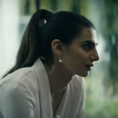 a woman in white shirt sitting next to a window