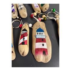 wooden key chains with painted lighthouses on them sitting next to other wood pegs