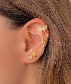 a close up of a person wearing gold ear piercings with flowers on it's side