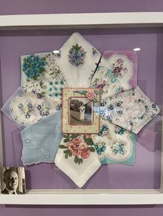 a display case with various handkerchiefs and pictures on it's sides, along with a small photo frame