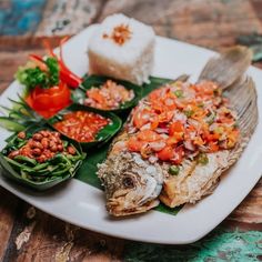 a white plate topped with fish and vegetables