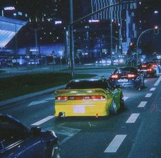 cars are driving down the street at night in an urban area with tall buildings and skyscrapers