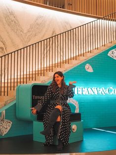 a woman is sitting on a bench in front of a blue wall with many butterflies