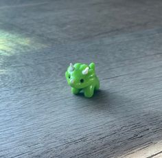 a small green toy animal sitting on top of a wooden table