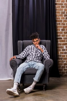 a man sitting in a chair with his hand on his chin