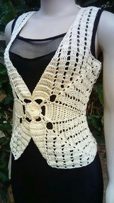 a mannequin wearing a white crocheted vest and black tank top with an open back