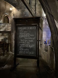 a chalkboard with writing on it in a stone walled room next to an arched doorway