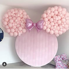 a pink mickey mouse balloon wall with balloons attached to it's ears and bows