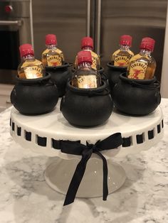 several bottles of whiskey are in black shoes on a white cake stand with a bow