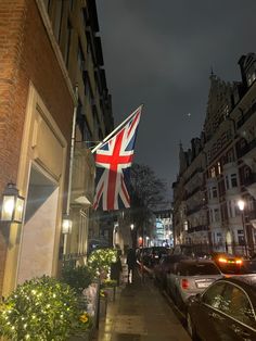 a british flag is hanging on the side of a building in an urban area at night