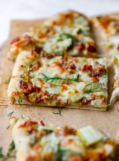 several slices of pizza sitting on top of a wooden cutting board with herbs and other toppings