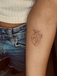 a person with a heart tattoo on their left arm and the other arm behind her