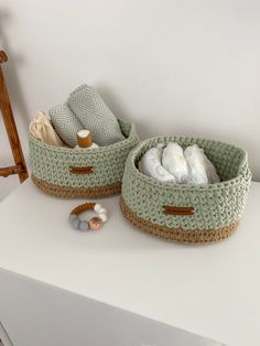 two baskets are sitting on top of a white table and one is filled with items