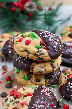 chocolate chip cookies with candy and sprinkles on a plate next to christmas decorations