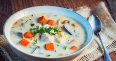 a white bowl filled with soup on top of a wooden table next to a spoon