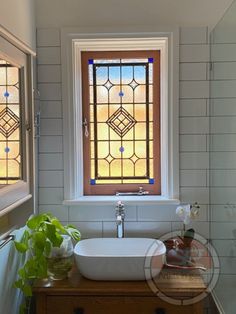 a white sink sitting under a window in a bathroom