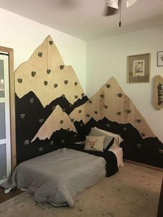 a bed room with a neatly made bed and mountains on the wall