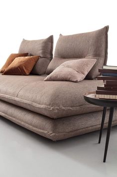 a couch that has some pillows on it and is next to a table with books