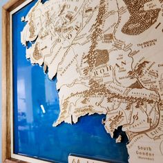 a wooden map is hanging on the wall in front of a blue glass frame with writing