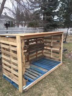 a wooden pallet with blue slats on the top and bottom part, in front of some trees