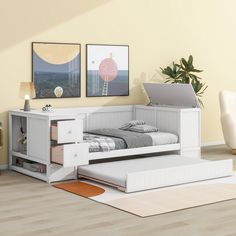 a bedroom with a bed, desk and laptop on the floor in front of two pictures