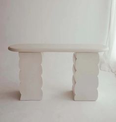 a white bench sitting on top of a white floor next to a curtained window