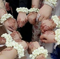 several people with henna on their hands and white flowers in the middle of them