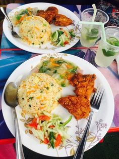 two white plates topped with different types of food and silverware next to each other