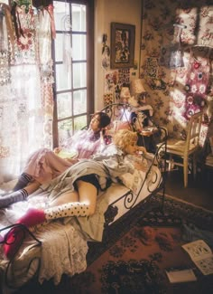 two women laying on a bed in a room with floral wallpapers and curtains