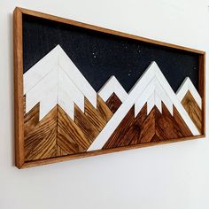 a wooden frame with mountains painted on the side and stars in the sky above it