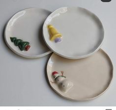 two white plates with christmas decorations on them and one has a yellow cone in the middle