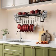 a kitchen with green cabinets and white countertops has pots and pans hanging on the wall