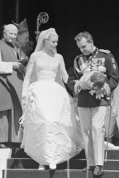 an old black and white photo of a bride and groom walking down the stairs together