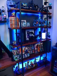 a book shelf filled with lots of books on top of a wooden floor next to a blue light