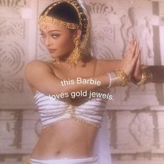 a woman in a white and gold costume with her hands on her hips while wearing jewelry