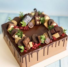 a heart shaped cake with chocolates and berries on it's side, sitting on a table