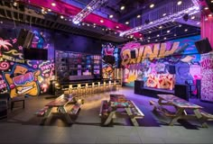 a room filled with lots of tables covered in colorful lights and graffiti on the walls