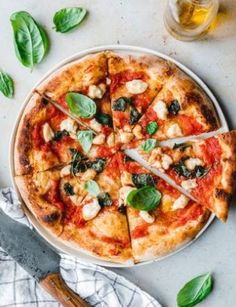 a pizza on a plate with several slices cut out and sitting next to a glass of beer